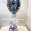 Arranjo decorativo para chá revelação com balão preto decorado, mini balões coloridos, base com pelúcia e detalhes harmoniosos.