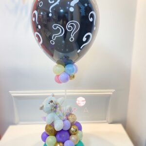 Arranjo decorativo para chá revelação com balão preto decorado, mini balões coloridos, base com pelúcia e detalhes harmoniosos.
