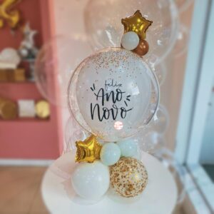 Decoração de Ano Novo com bolha transparente personalizada, glitter dourado e base de balões desconstruídos com mini estrela metalizada.