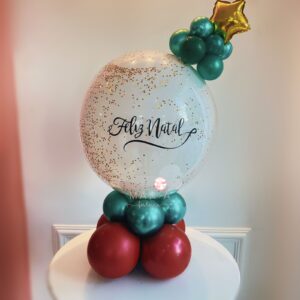 Balão natalino personalizado com mini árvore no topo, base em balões desconstruídos e detalhes lúdicos.