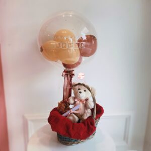 Arranjo de maternidade com ursinho de pelúcia, cesta decorada e balão personalizado com o nome do bebê, adaptável para meninos e meninas.
