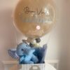 Kit de boas-vindas com elefantinho de pelúcia azul, balão transparente personalizado com nome, e caixa decorativa com estampa de ovelhas.