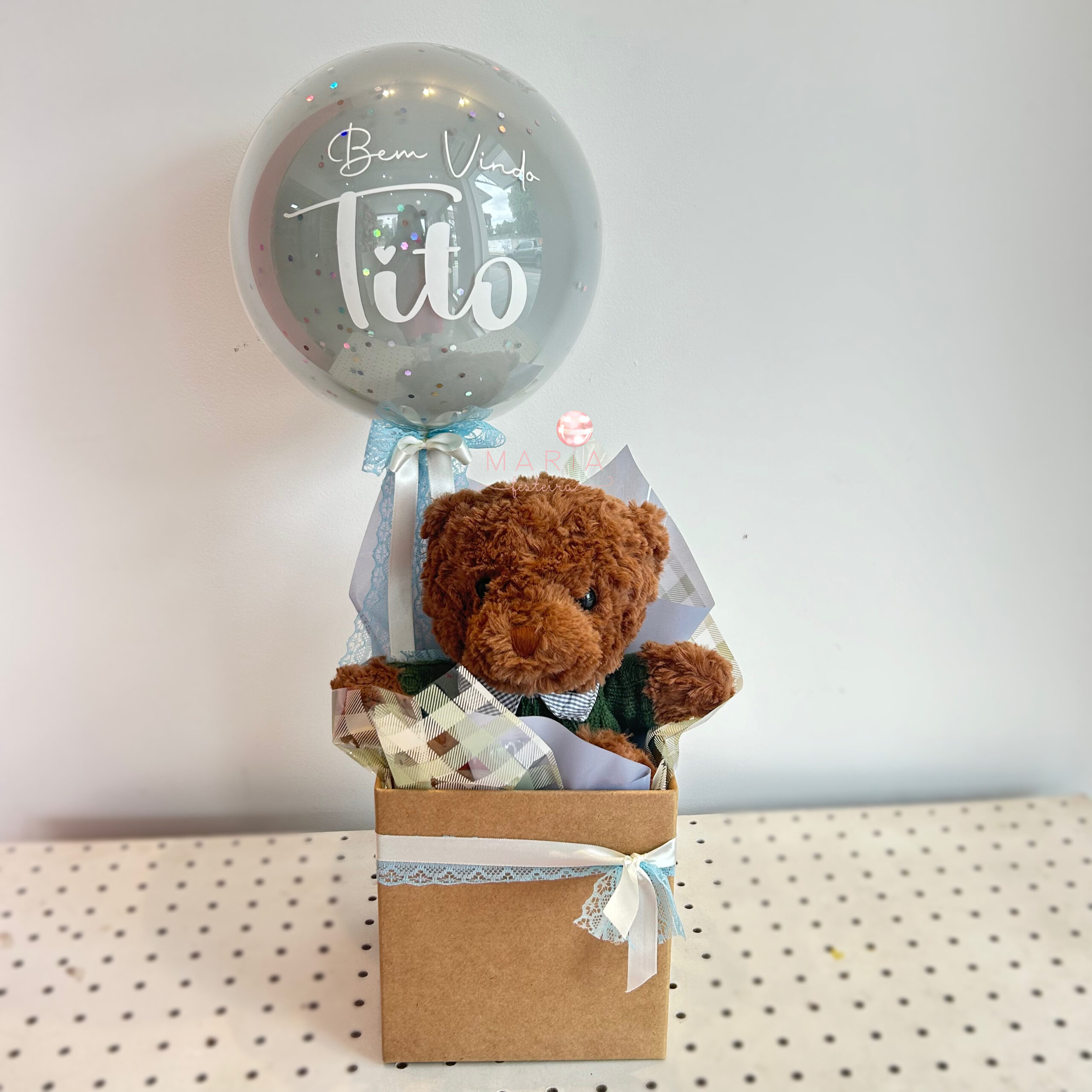 Arranjo de boas-vindas com ursinho de pelúcia em caixa decorada e balão transparente personalizado com nome.