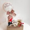Cesta natalina personalizada com ursinho de pelúcia, balão decorado com confetes dourados e mensagem de Feliz Natal, espumante e bombons Ferrero Rocher.