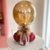 Arranjo de Natal elegante com balão bubble transparente, balões internos coloridos, base com mini balões natalinos e laços decorativos.