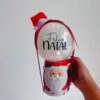 Kit natalino com caneca de Papai Noel, mini bubble com "Feliz Natal", gorro e laço decorativo. Perfeito para presentear ou decorar no Natal.