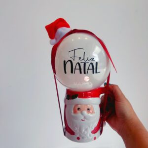 Kit natalino com caneca de Papai Noel, mini bubble com "Feliz Natal", gorro e laço decorativo. Perfeito para presentear ou decorar no Natal.